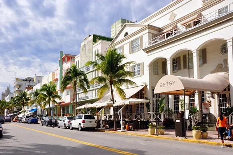 Miami cruise deal featuring a ship approaching the city’s vibrant skyline, palm-lined beaches, and bustling PortMiami along the Atlantic coast