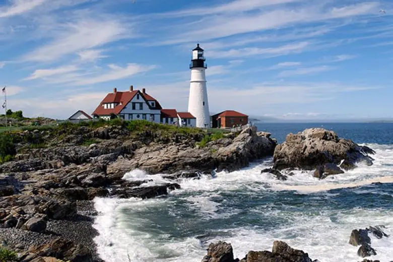 Canada and New England cruise deal featuring a ship sailing past rocky coastlines, charming harbors, and colorful fall foliage with historic lighthouses in view