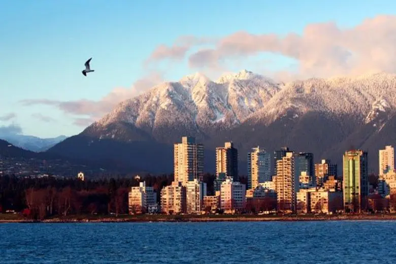 Vancouver cruise deal showcasing a ship departing Canada’s west coast with views of coastal mountains, evergreen forests, and the city’s scenic skyline